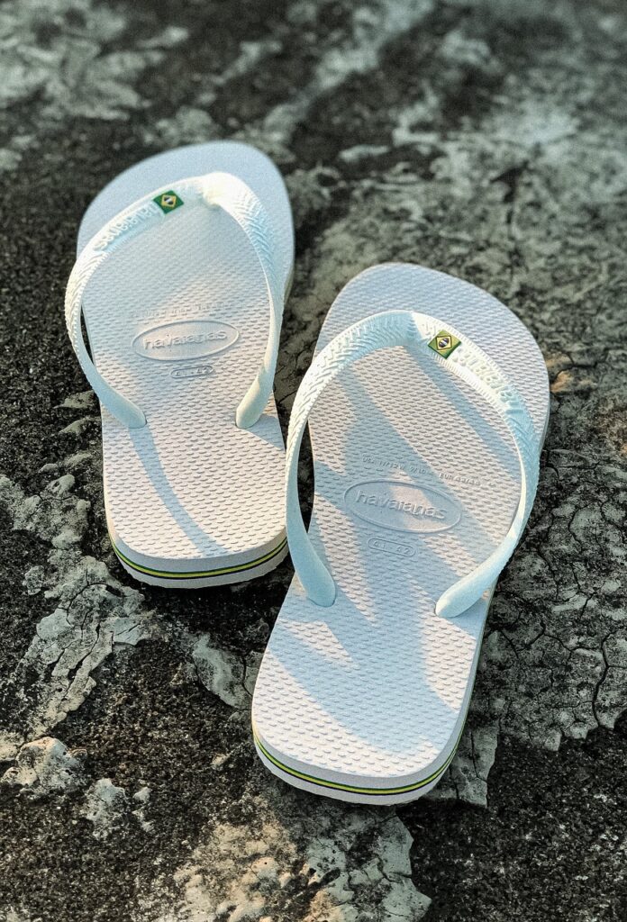A pair of elegant white flip-flops placed on a smooth surface, perfect for casual and beachwear.